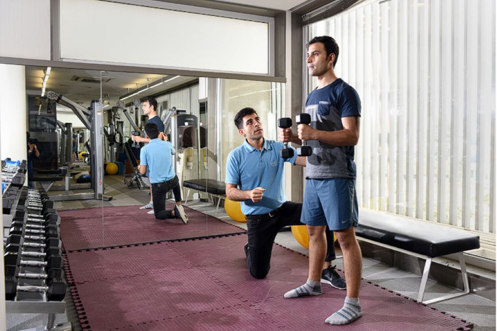 VARDĀN trainer assisting a man with exercises with strength training equipment