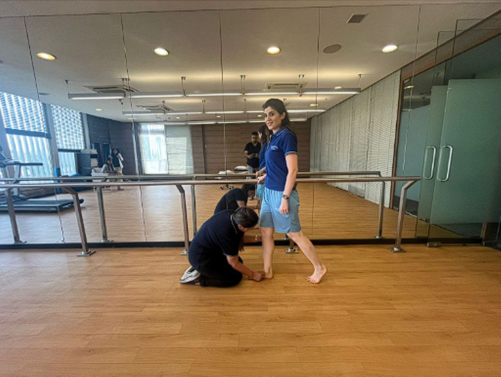 Professional physiotherapist applying targeted FMT techniques to a patient's ankle and foot during a clinical rehabilitation session.
