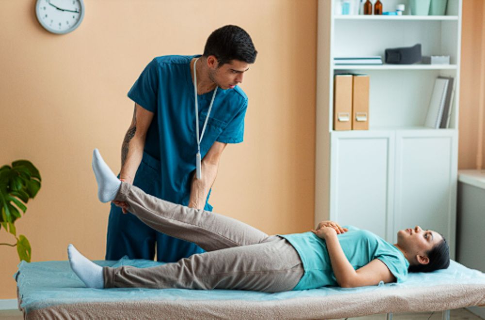 Male physiotherapist performing leg mobility assessments and stretching on a patient using FMT, showcasing comprehensive pain management in Delhi.